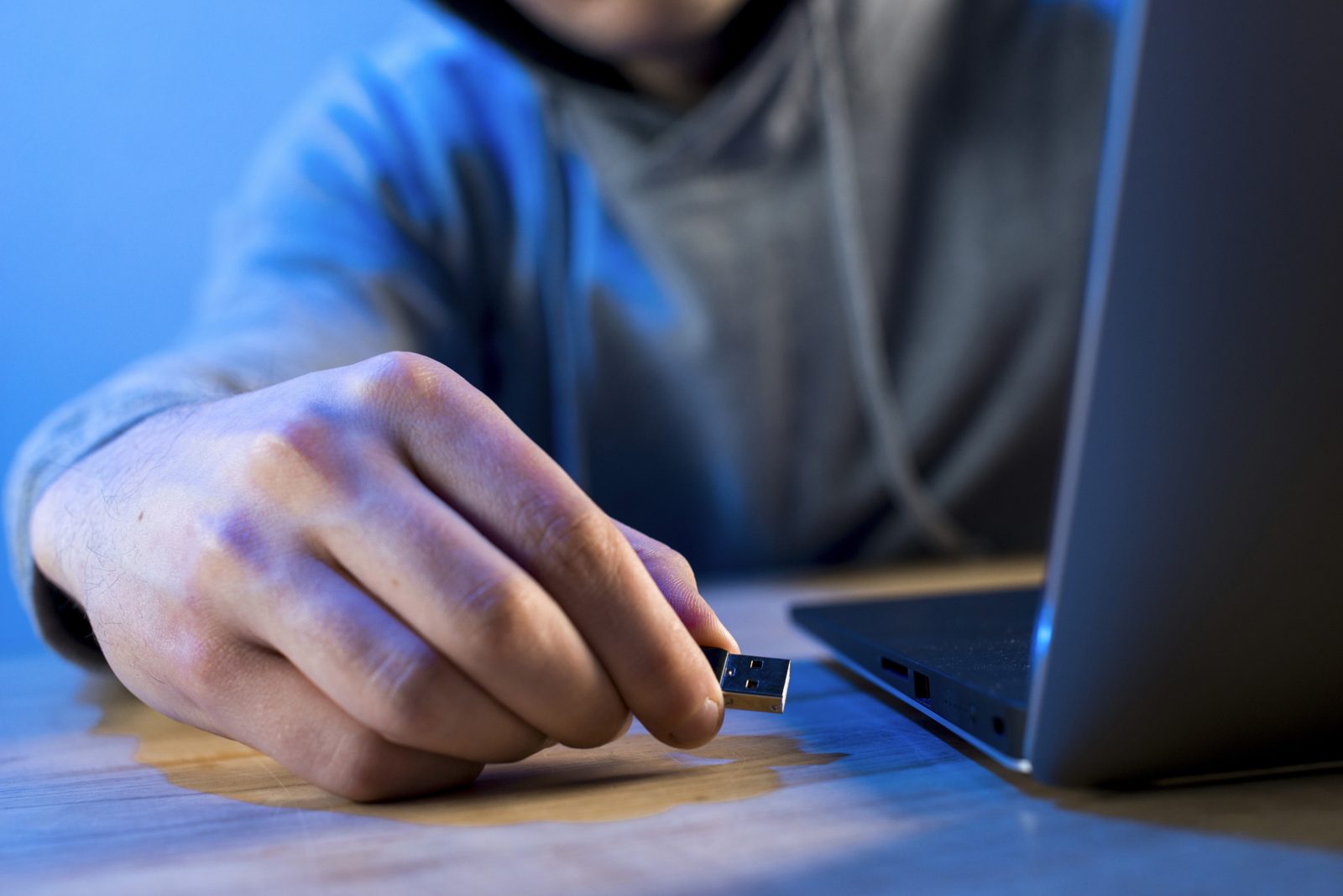 Hand steekt een usb-stick in een laptop, beeld bij een securitytest